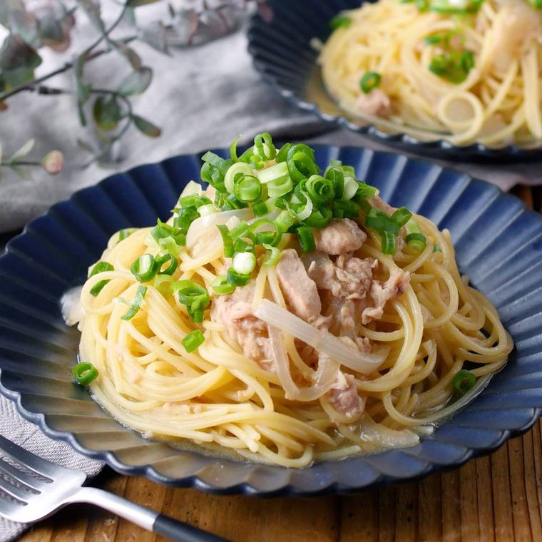 ネイビーの丸皿に盛りつけられた玉ねぎとツナの和風パスタ