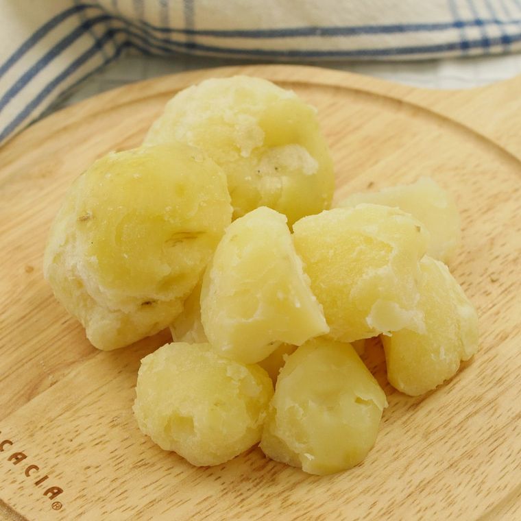 カッティングボードにのっているゆでたじゃがいも