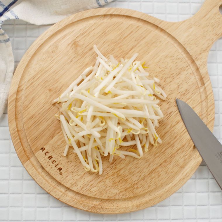 もやしがのった丸い木のまな板が、白いタイルのテーブルの上に置かれている