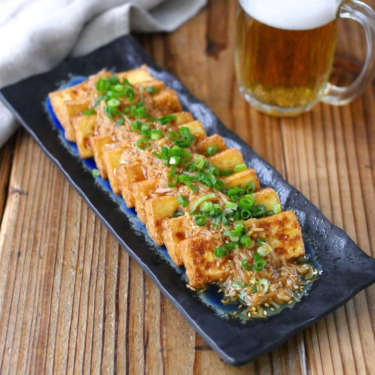 黒い器に盛り付けたなめ茸の厚揚げステーキとビール