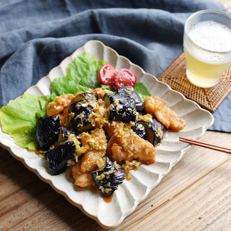 白い器に盛り付けた素揚げなすとささみの香味たれの油淋鶏と飲みもの