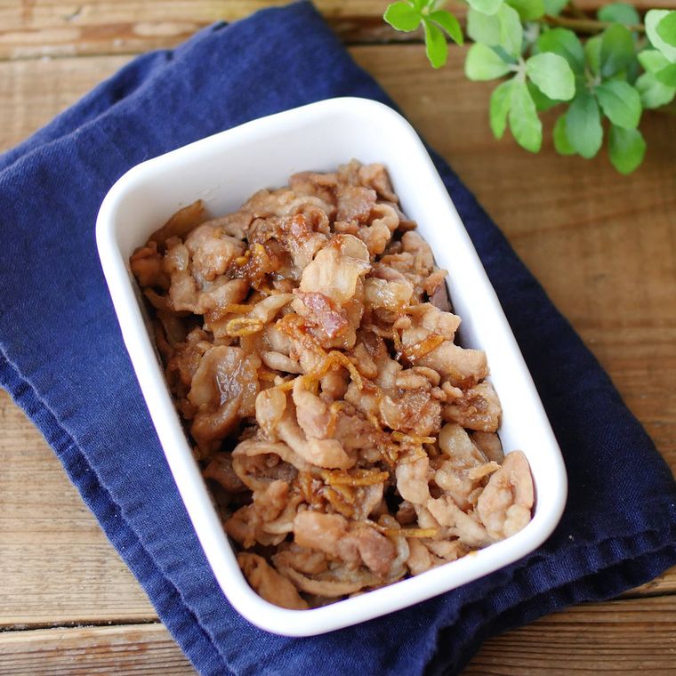 保存容器に入った豚こま肉の甘辛しぐれ煮と紺色の布