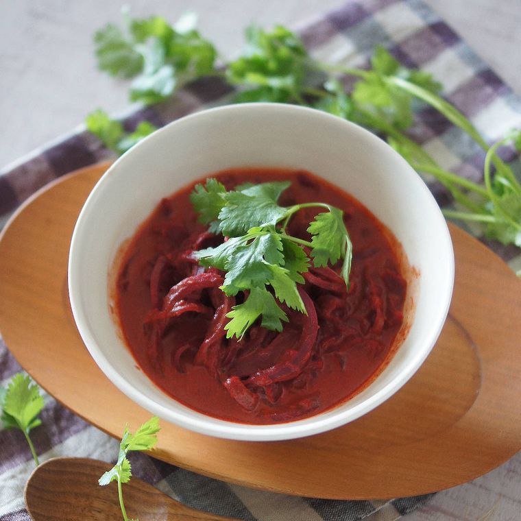 白い器に盛り付けられたビーツヌードル入りカレースープ