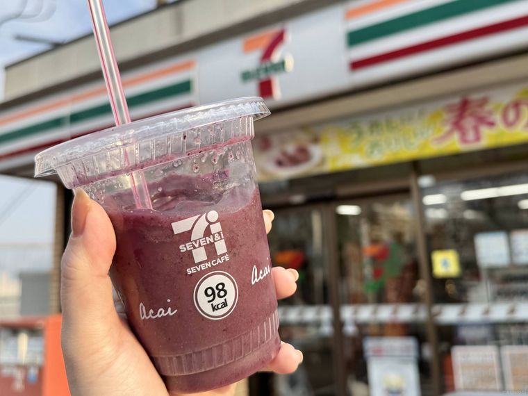 セブンイレブンを背景にアサイーバナナスムージーを持っている様子