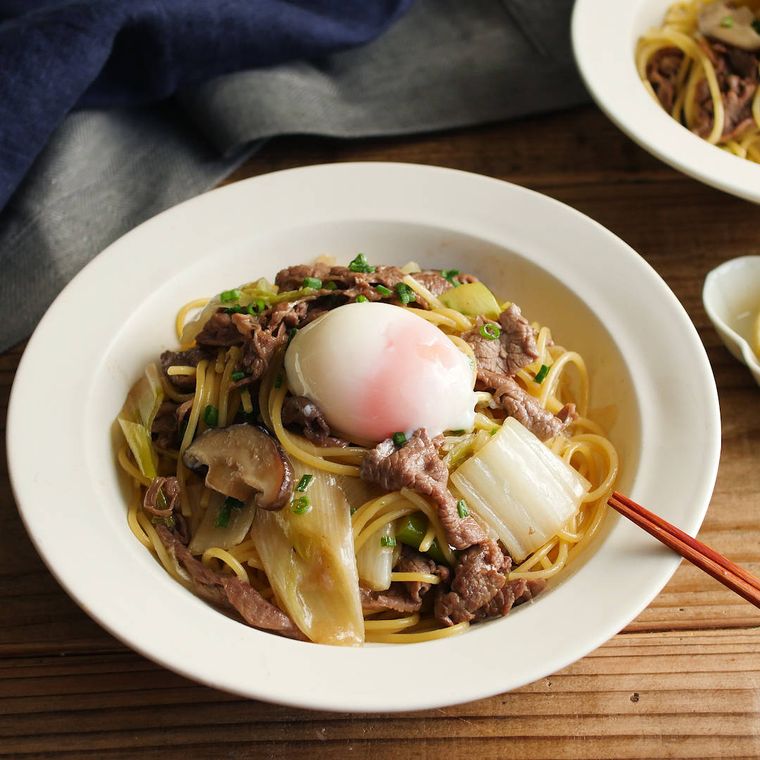 温泉卵をのせたすき焼き風パスタの入った白い皿