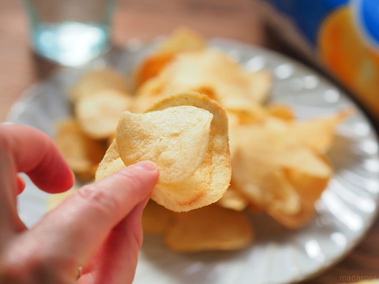 二枚の山芳 ポテトチップス ネオバターロール味を持つ様子