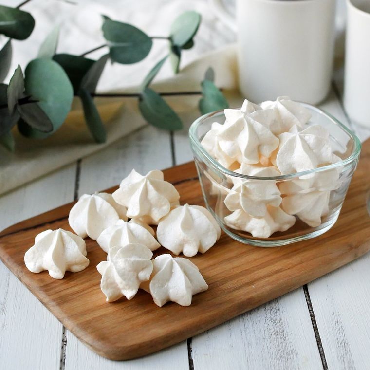 ガラスの保存容器にいれて、木製トレーに置かれたメレンゲクッキー