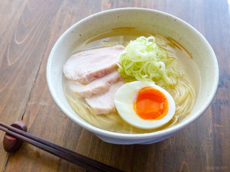 ゆで卵とネギ、鶏ハムをトッピングした塩ラーメンがあるテーブル