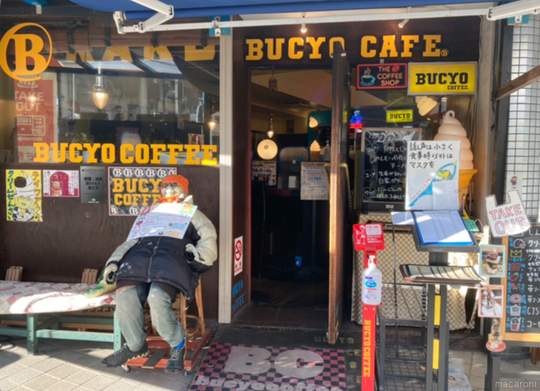 ブチョー コーヒーの黄色い文字とガラス張り、マスコット人形がある外観