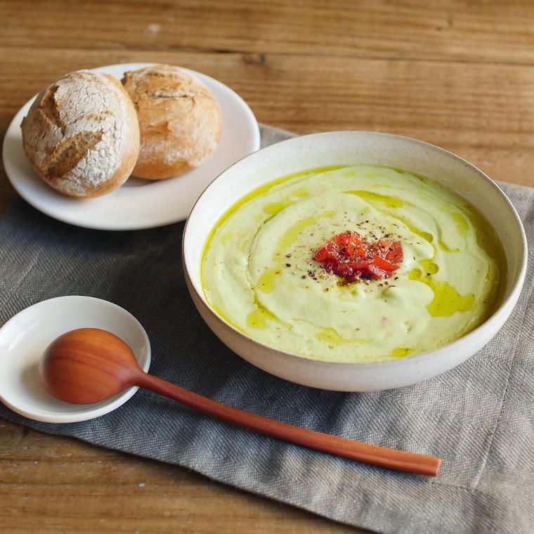 器に盛られたアボカドの冷製ヨーグルトスープと、皿にのったパン