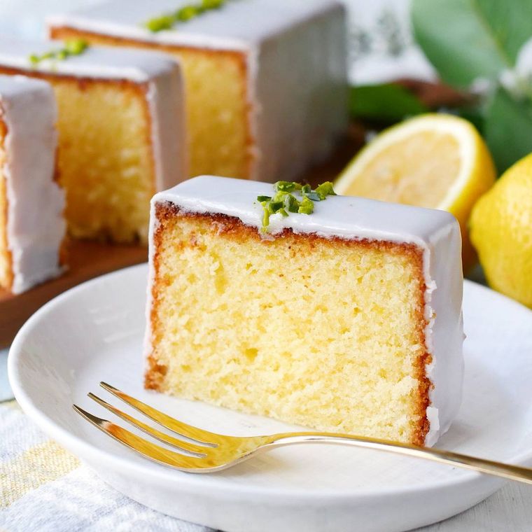 白い皿に盛りつけた、アイシングのかかったレモンパウンドケーキ、フォーク