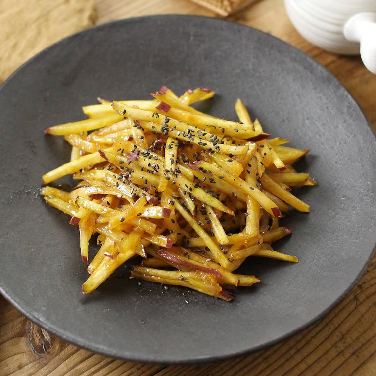 黒灰色の皿に盛りつけられた細切りジンジャー大学いも