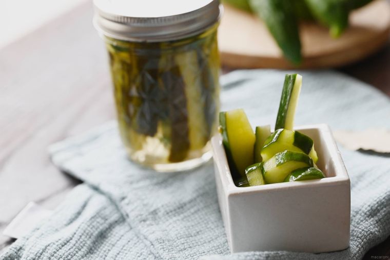保存瓶と白い皿に入ったきゅうりのハーブピクルス
