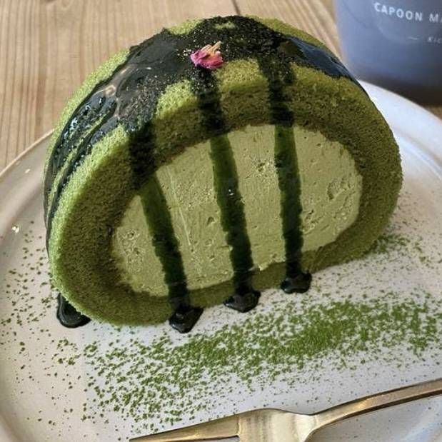 緑色の鮮やかな生地と生クリーム、シロップのかかった抹茶ロールケーキ