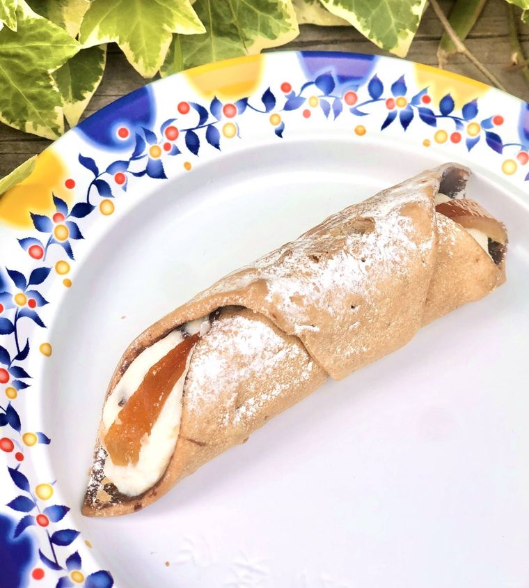 イタリア柄のお皿にのったカンノーリに植物が添えられている様子