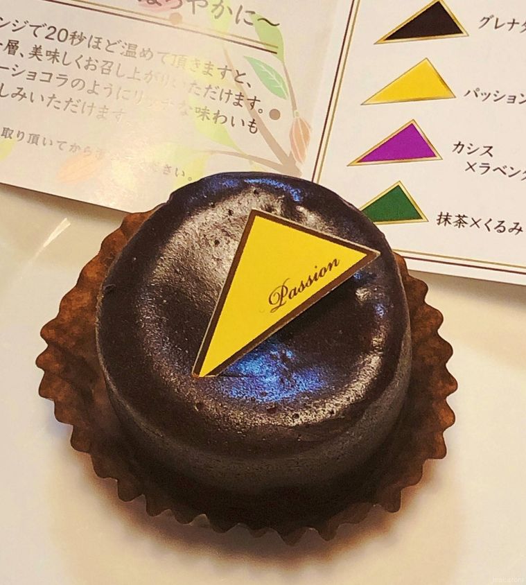 黄色いピックののった丸いチョコレートケーキの奥に、メニュー表が置かれている様子
