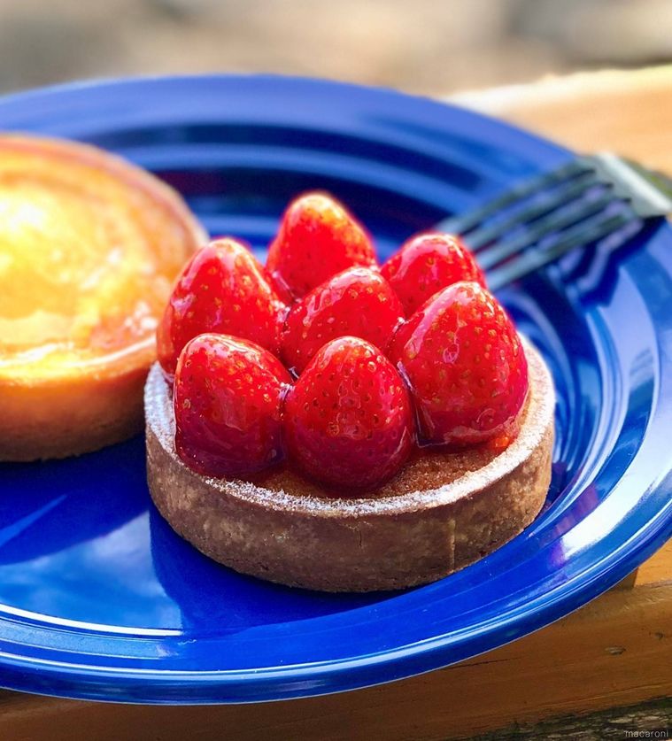 青いお皿に苺のタルトとエッグタルトがのっており、フォークが添えられている様子