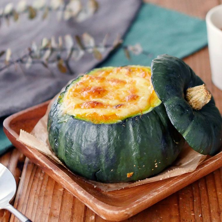 木製の角皿にのせられた、かぼちゃをくり抜いて作るかぼちゃグラタン