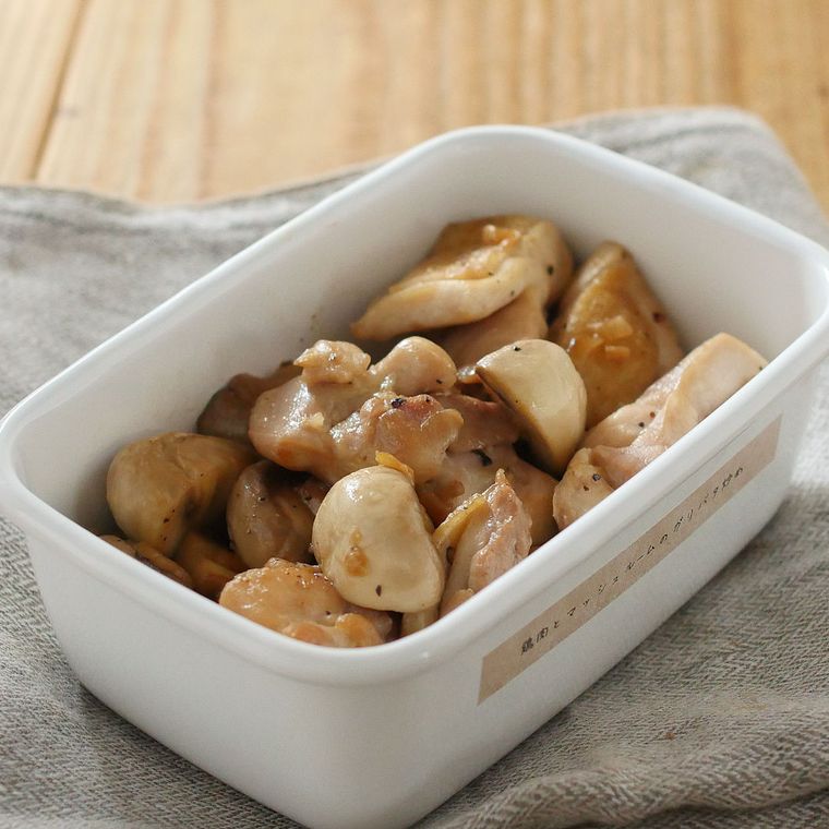 ホーロー容器に入った鶏肉とマッシュルームのガリバタ炒めの下にグレーのクロスが敷かれている様子