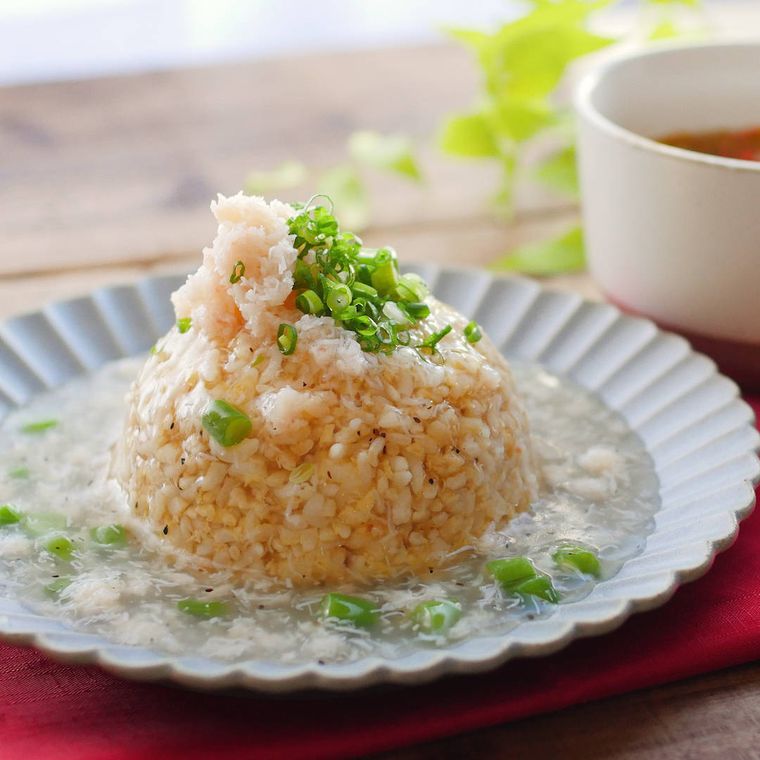 ふちがでこぼこしている白い丸皿に盛りつけられたカニといんげんのあんかけチャーハン