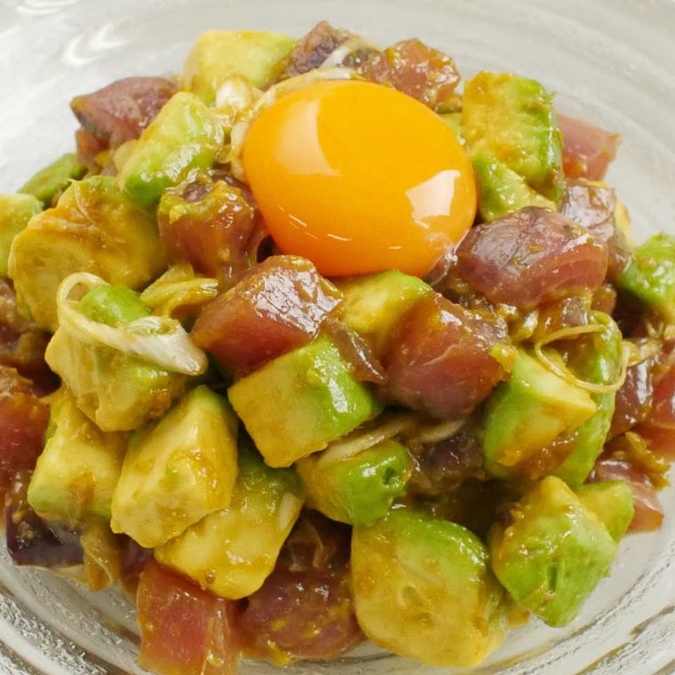 サイコロ型のカツオとアボカドを混ぜて山型に盛られ、卵黄がトッピングされてる