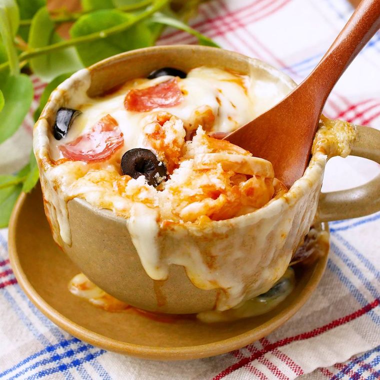 ベージュのマグカップで作ったマグカップピザをスプーンですくう様子