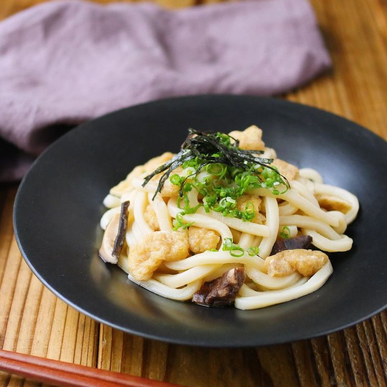 黒い皿に盛りつけられた油揚げとしいたけの混ぜうどん