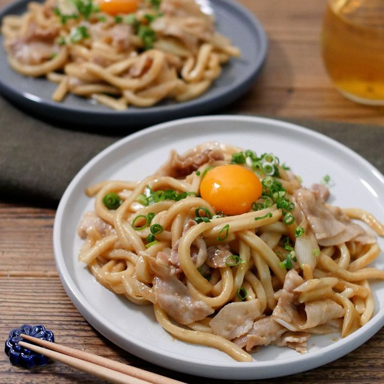白い皿に盛りつけられた豚バラ肉と長ねぎの混ぜうどん