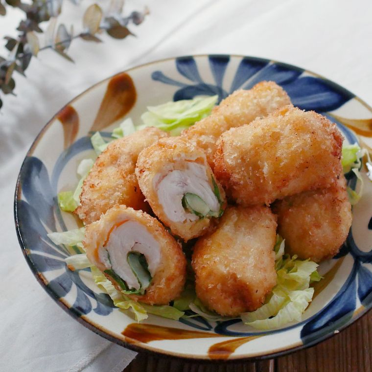 青色と茶色の模様が入った丸皿に盛られた鶏胸肉のチーズロールフライ