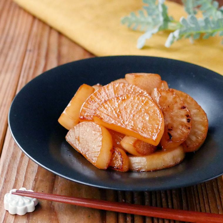黒い皿に盛りつけられた大根のバターしょうゆ煮