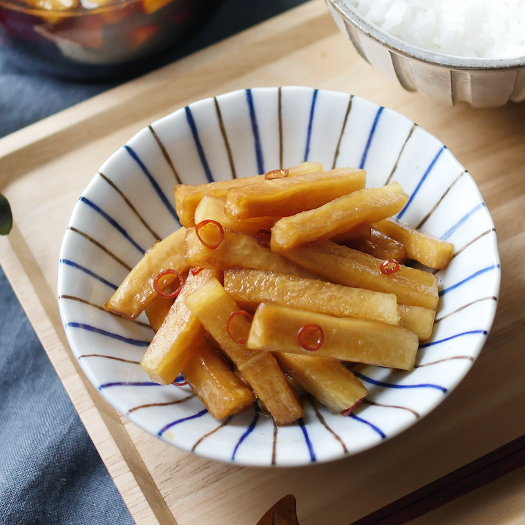 ストライプ入りの皿に盛りつけられた大根の甘辛だれ漬け