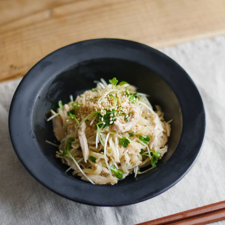 黒い丸皿に盛り付けた柚子ポン酢しょうゆがけの切り干し大根と鶏ささみのサラダ