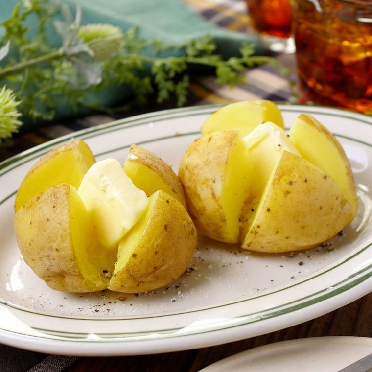 白い楕円形の皿に新じゃがバターが2個盛られている