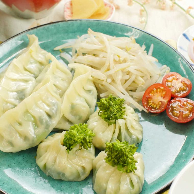 器に盛り付けたもやしとプチトマトと菜の花と海老の蒸し餃子