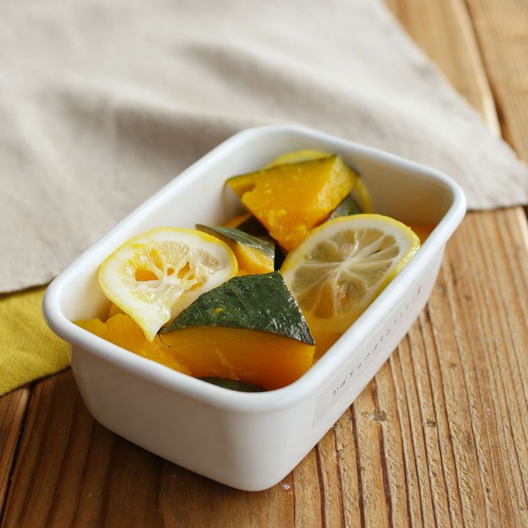 白い保存容器に入っているかぼちゃのはちみつレモン煮