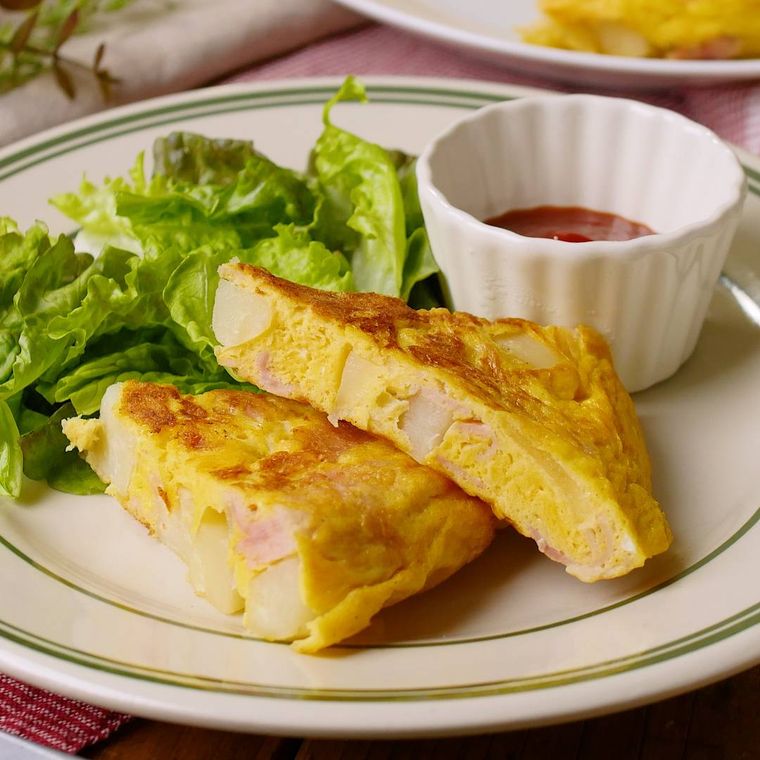 皿に盛りつけられたフリッタータにレタスとケチャップが添えられている