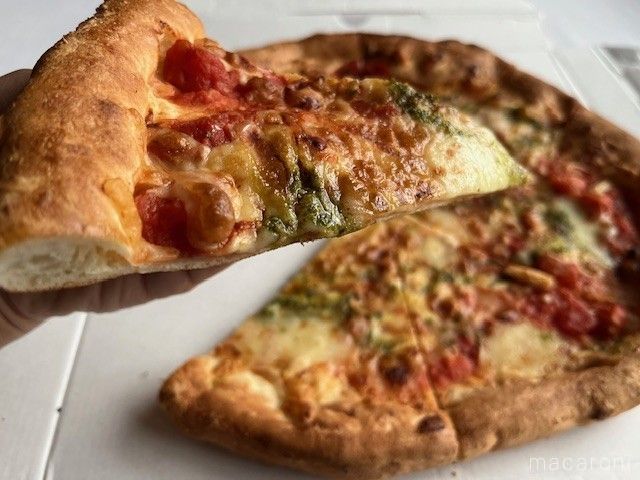 カットされたマルゲリータピザを持ち上げている