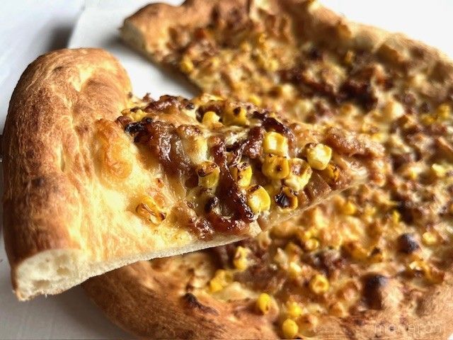 一切れのテリヤキチキンピザを持ち上げている