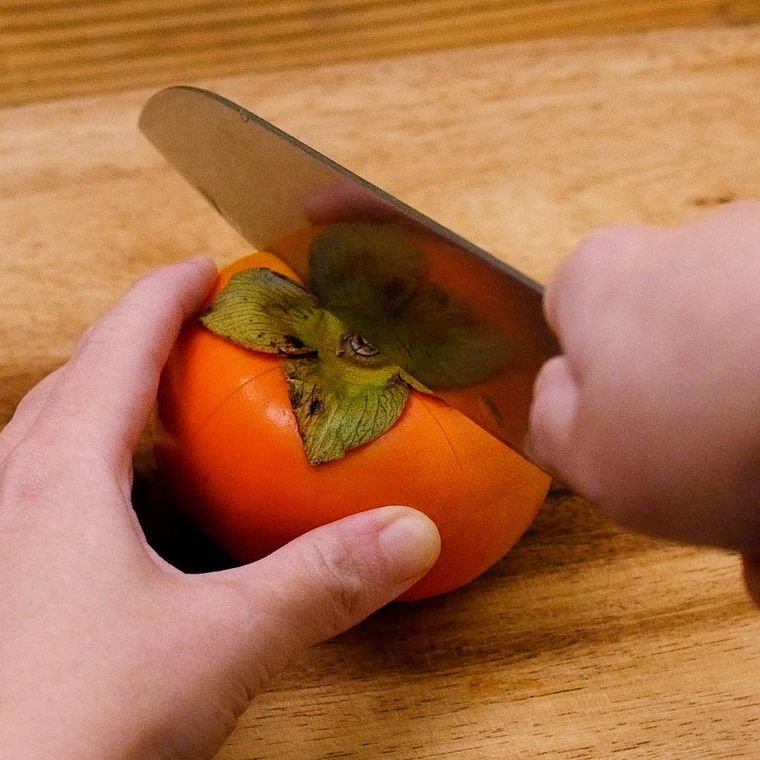 包丁で柿を切っている様子