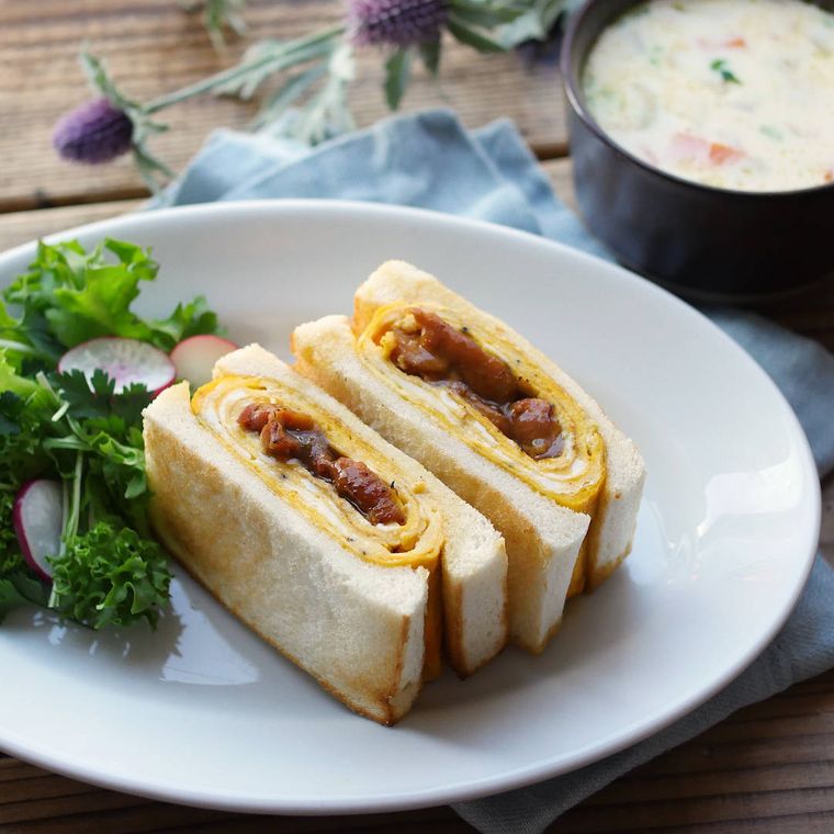 白い皿に盛りつけられた照り焼きチキン入りのオムレツサンド