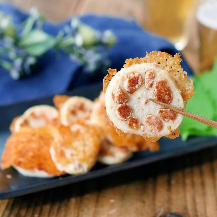 黒色の皿に盛られたれんこんの明太チーズ焼きを箸上げした様子