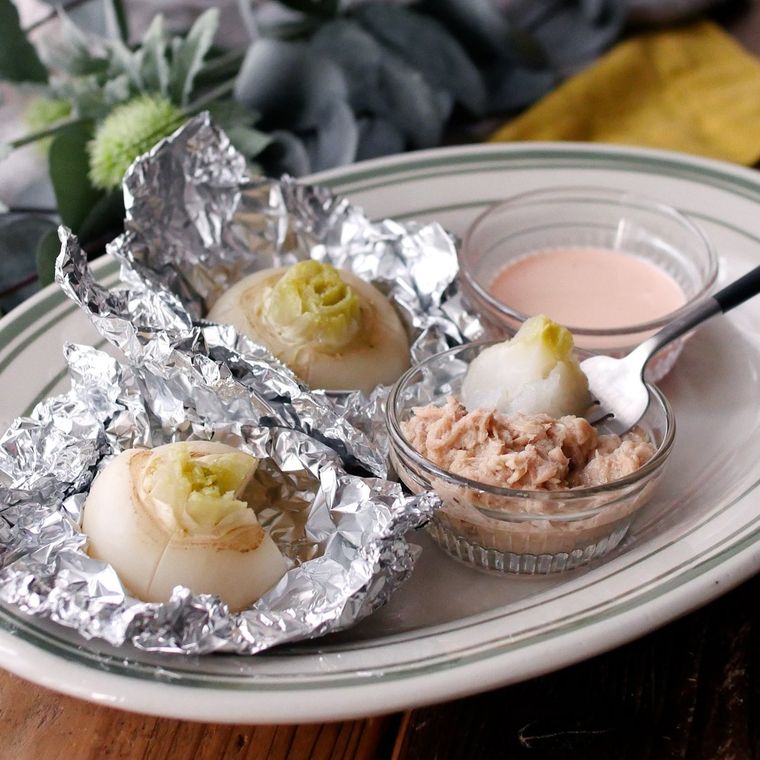 楕円形の皿に盛りつけられたカブのまるごとホイル焼きに二種のソースが添えられている