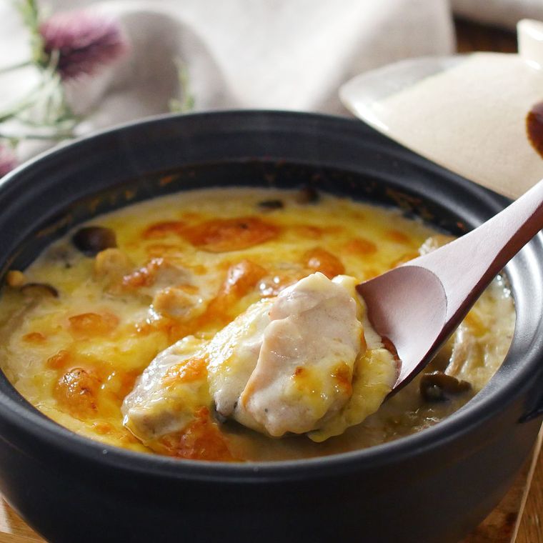 黒い土鍋に入っている鶏もも肉と玉ねぎ、しめじのペンネグラタン