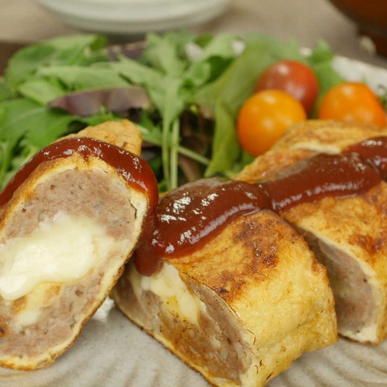 油揚げで巻かれたチーズメンチカツがサラダと一緒に皿に盛られていて、メンチカツの上にはソースがかかっている