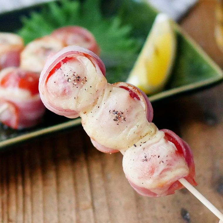 緑の皿に盛られたミニトマトのベーコン巻き