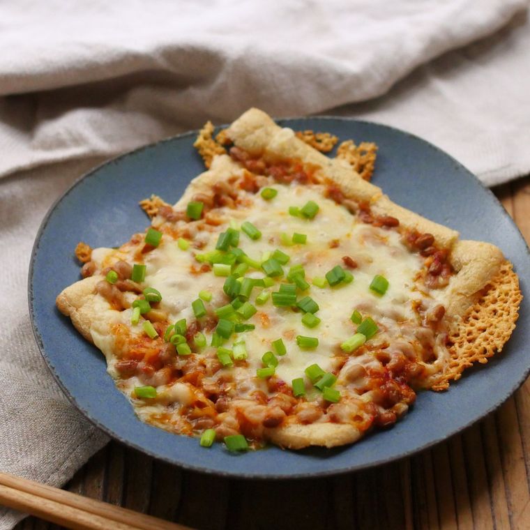 マットな青い皿に盛りつけられたキムチと納豆の油揚げピザ