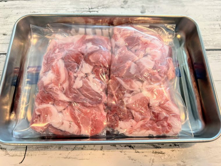 フリーザーバッグに入れてアルミトレイの上に置き、冷凍保存の準備をされた豚こま切れ肉