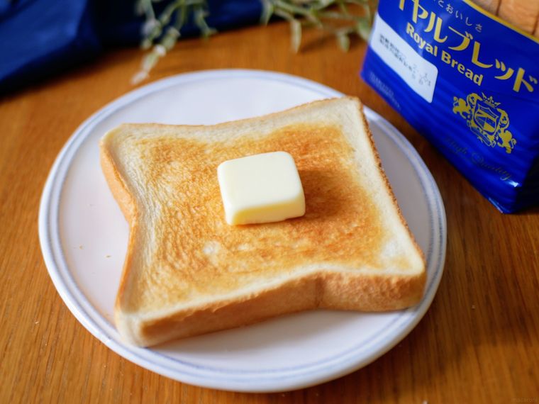 白い皿にバタートーストがのっており、奥に山崎製パンロイヤルブレッドのパッケージが見えている様子