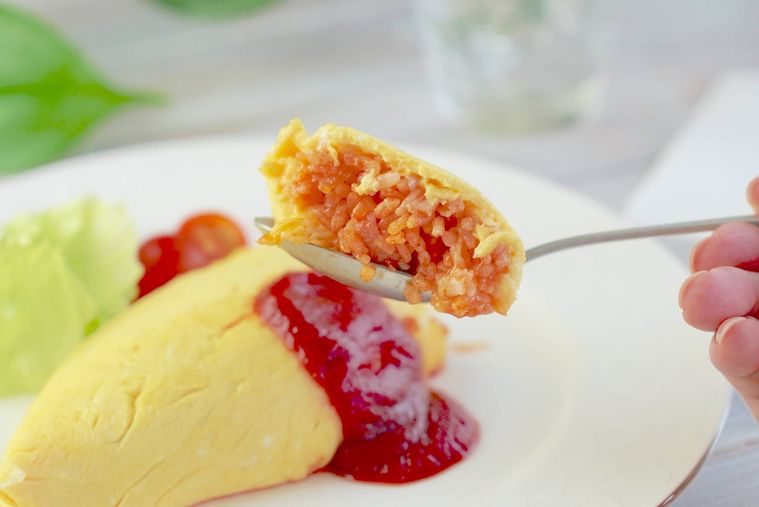 オムライスをスプーンで切って持ち上げている