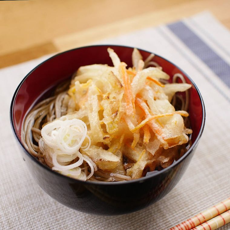 黒色の丼腕にかき揚げそばが盛りつけられている